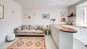 Un salon moderne avec un canapé, une table basse et un tapis. Il y a également un coin cuisine avec un comptoir et un évier.