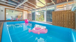 Une piscine intérieure à l’eau d’un bleu cristallin, un flotteur gonflable rose et un ballon d’exercice rose.