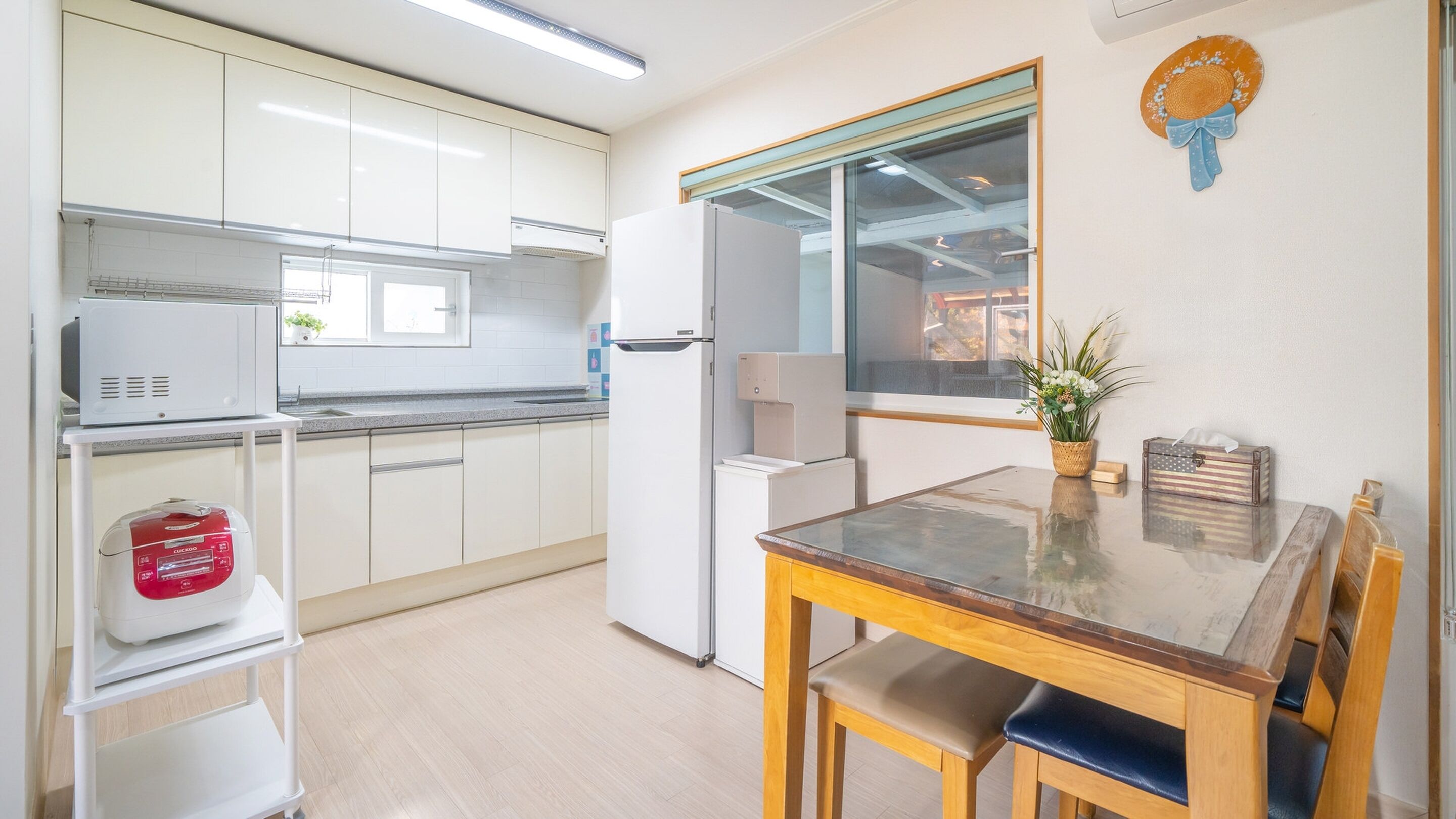 A compact kitchen with white cabinets, a microwave, a refrigerator, and a small dining table with chairs.