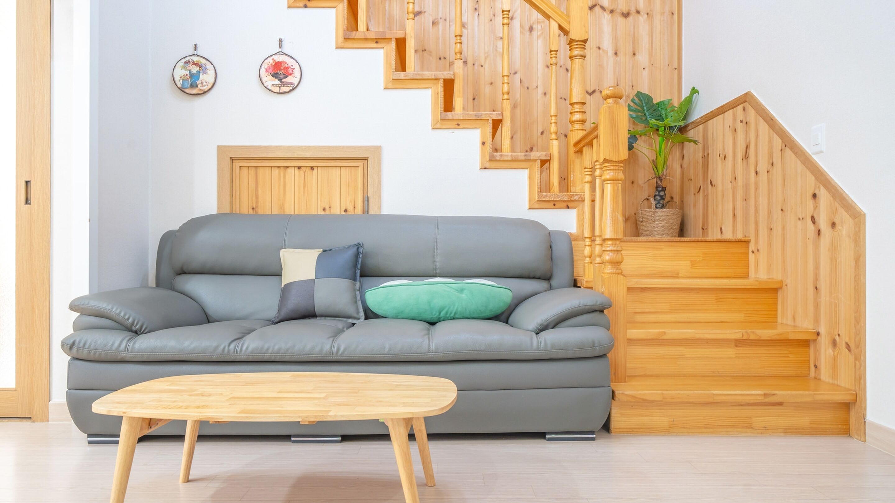 A living room with a grey sofa, a wooden coffee table, and a wooden staircase.