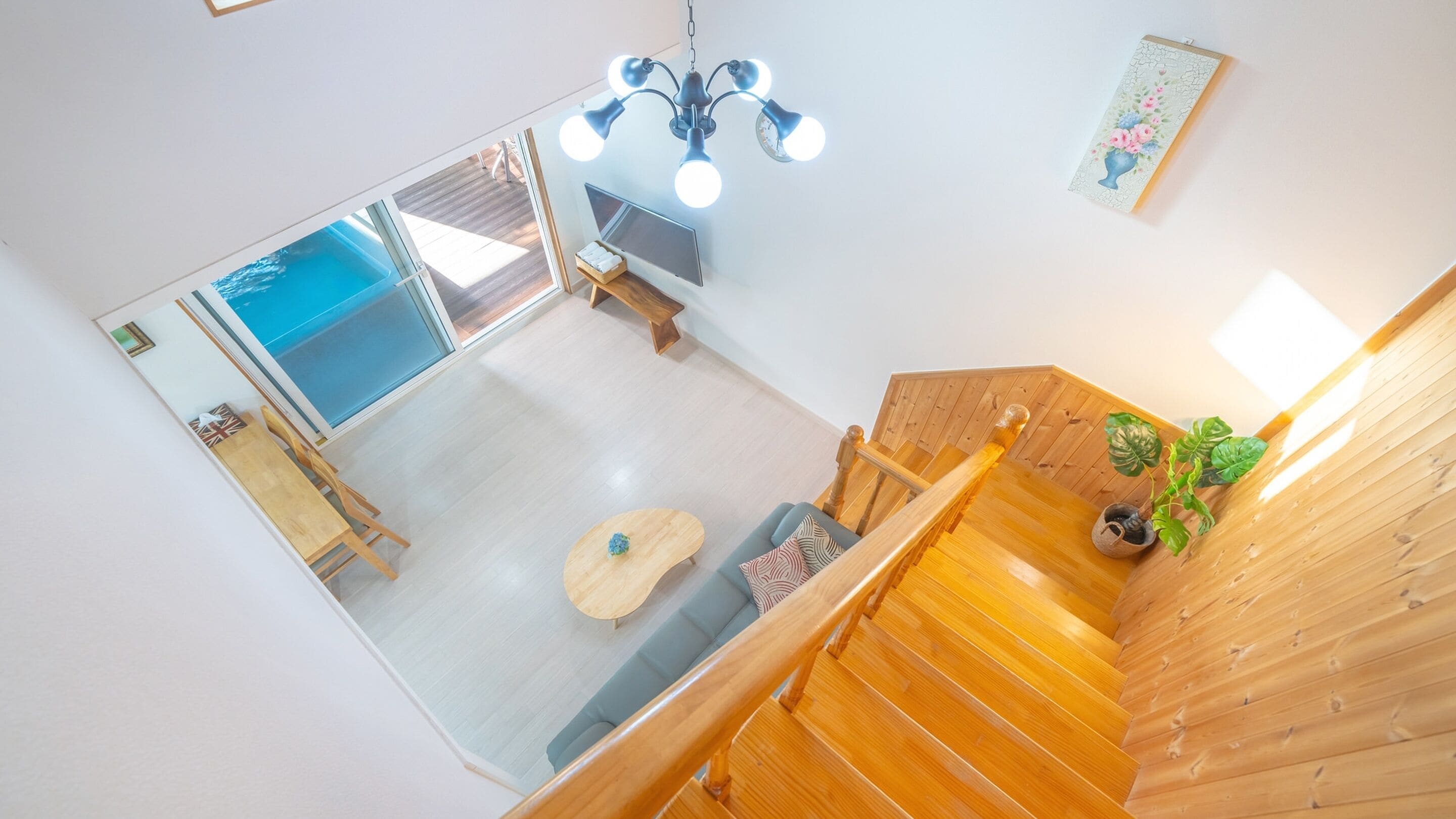 A spacious living area with a wooden staircase, a dining table, and a sofa.