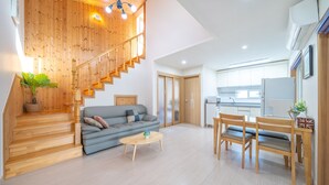 Ein modernes Wohnzimmer mit Treppe, einer Couch, einem Couchtisch und einem Essbereich.