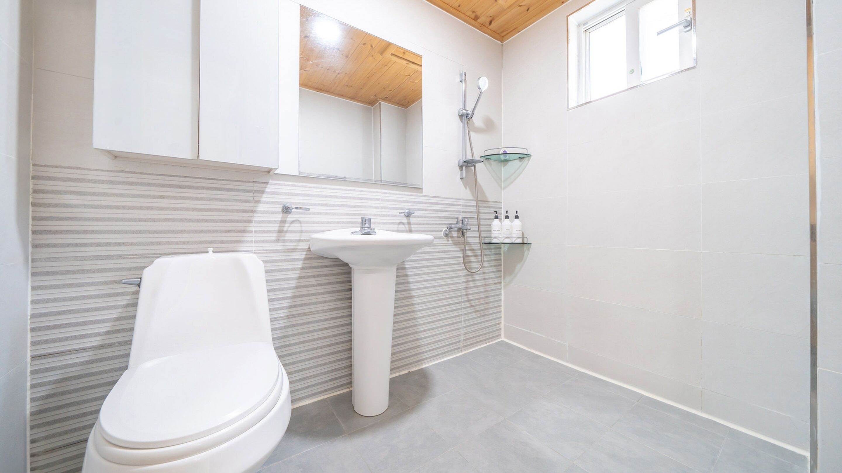 A modern bathroom with a toilet, sink, and shower.