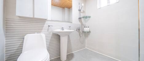 A modern bathroom with a toilet, sink, and shower.