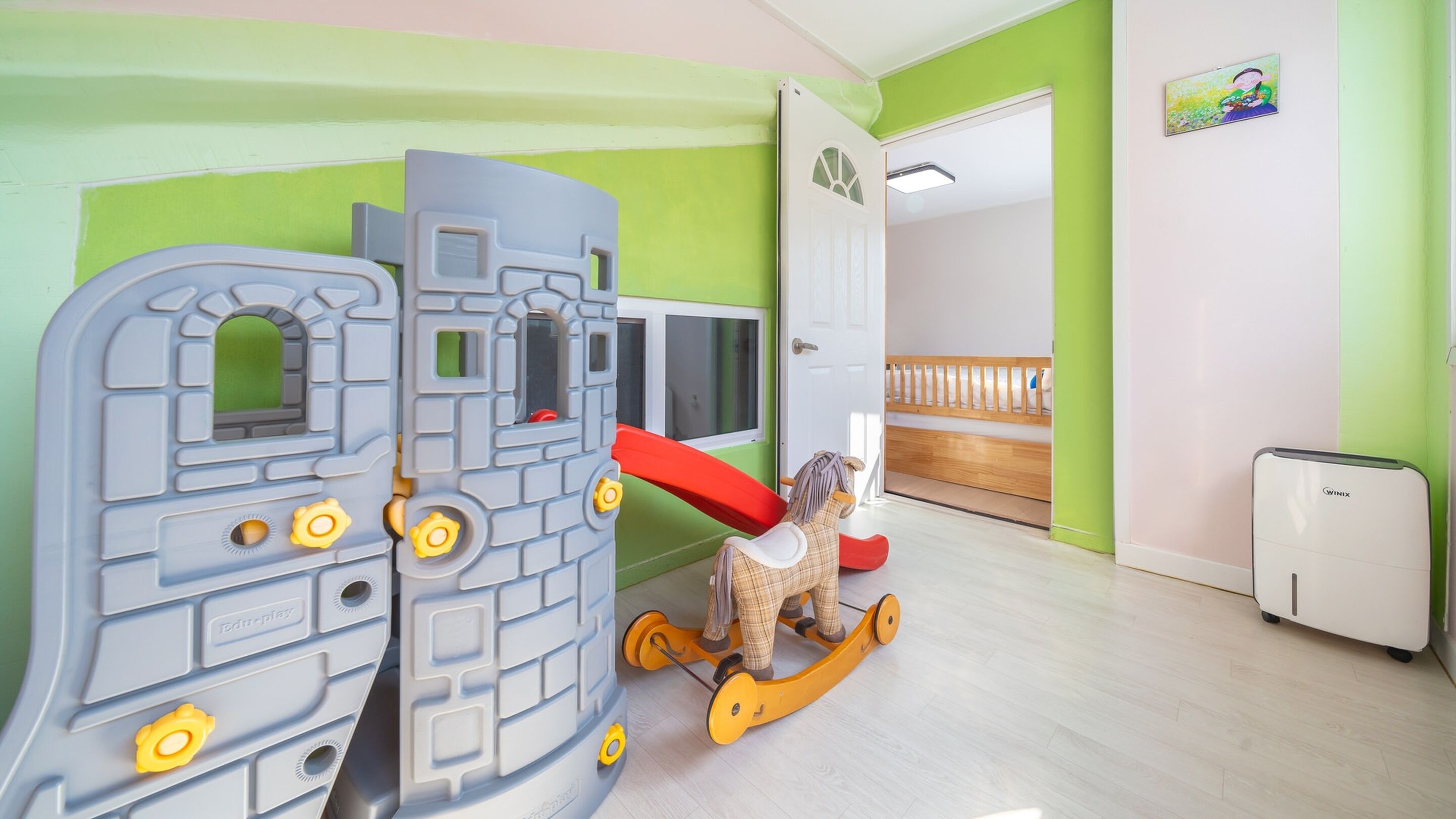 A child's play area with a playhouse, a rocking horse, and a white appliance.
