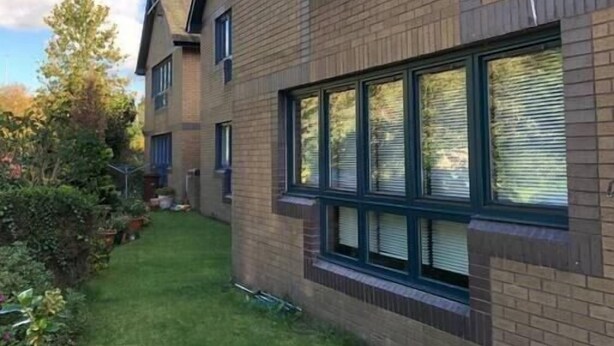 A two-story building with a brick facade, large windows, and a small front yard with grass and plants. - NEW Super 2BD Flat near Dalkeith Town Centre (Midlothian)