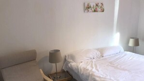 A hotel room with a bed, a chair, a small table with a lamp, and a wall-mounted picture. - NEW Super 2BD Flat near Dalkeith Town Centre (Midlothian)
