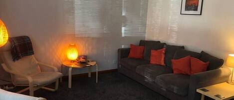 A living room with a sofa, armchairs, a small table, and a lamp.