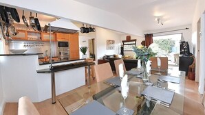 A modern kitchen with stainless steel appliances, a dining area with a glass table, and a view of the outdoors. - Gorgeous 3BD Cottage with Parking Nr Guildford (Surrey)