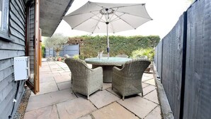 An outdoor patio with a round table and two wicker chairs, an umbrella, and a concrete floor. - Gorgeous 3BD Cottage with Parking Nr Guildford (Surrey)