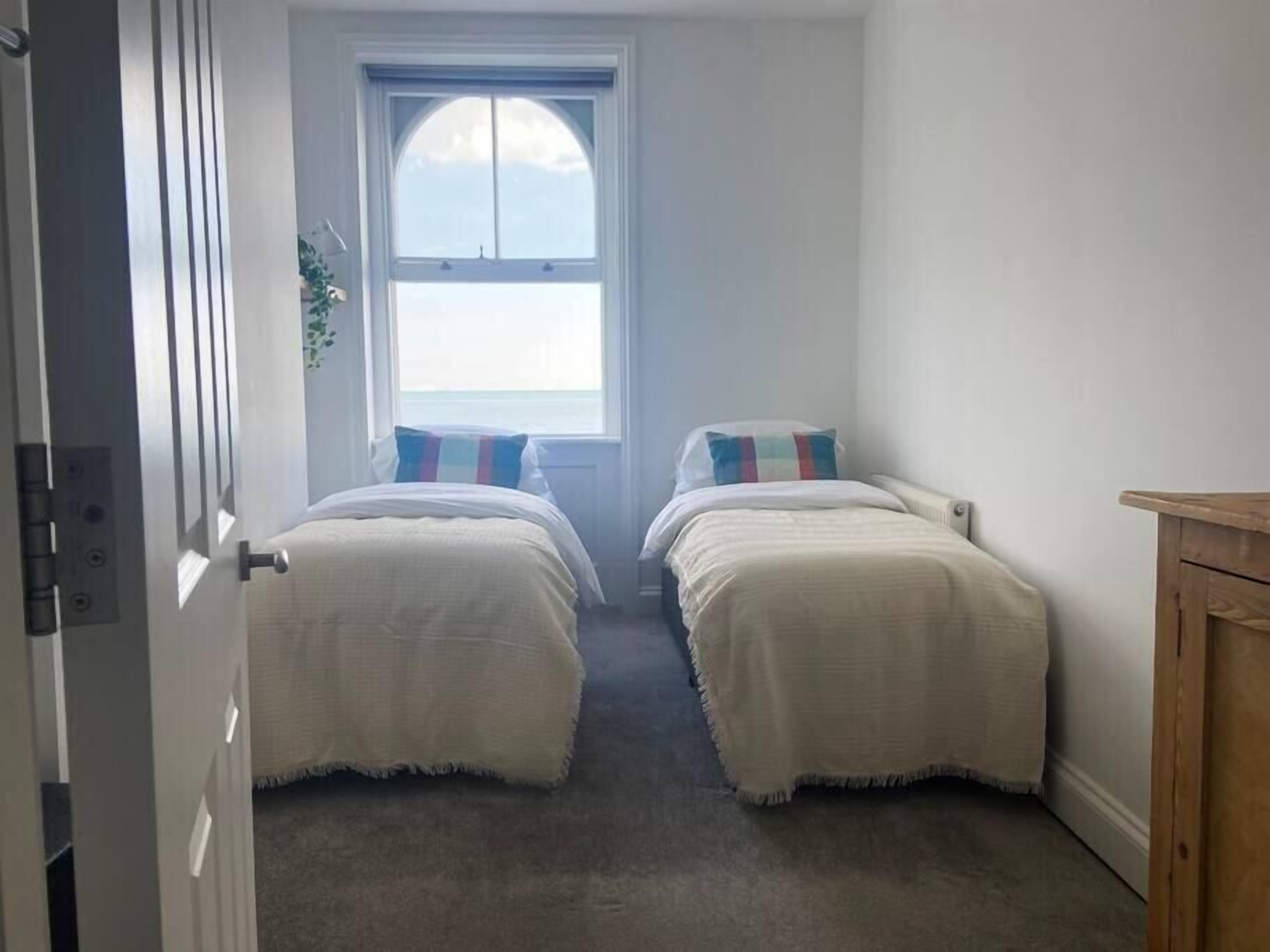 A bedroom with two beds, a window with a view, and a wooden cabinet.