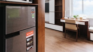 A modern kitchen with a microwave, refrigerator, and wooden cabinets. - HoLo Central Hanoi - Serviced HomeStay (Hanoi)