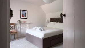 A bedroom with a large bed, a chair, a desk, and a framed picture on the wall. - Fantastic 2BD Victorian Apt - 4 adults and 1 child (East Sussex)