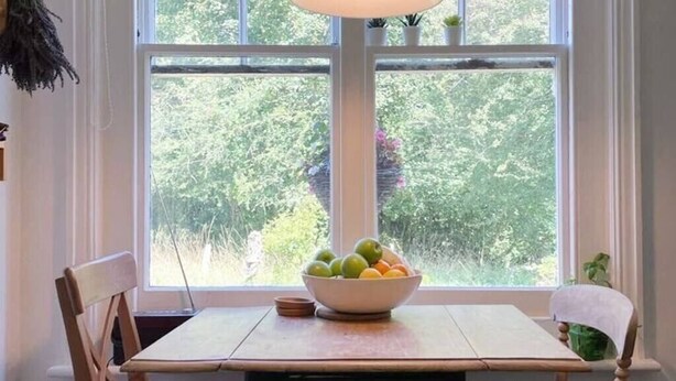 A dining table with a bowl of fruit in front of a window with a view of greenery. - Fantastic 2BD Victorian Apt - 4 adults and 1 child (East Sussex)