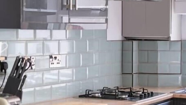 A modern kitchen with a gas stove, wooden countertop, and stainless steel appliances.