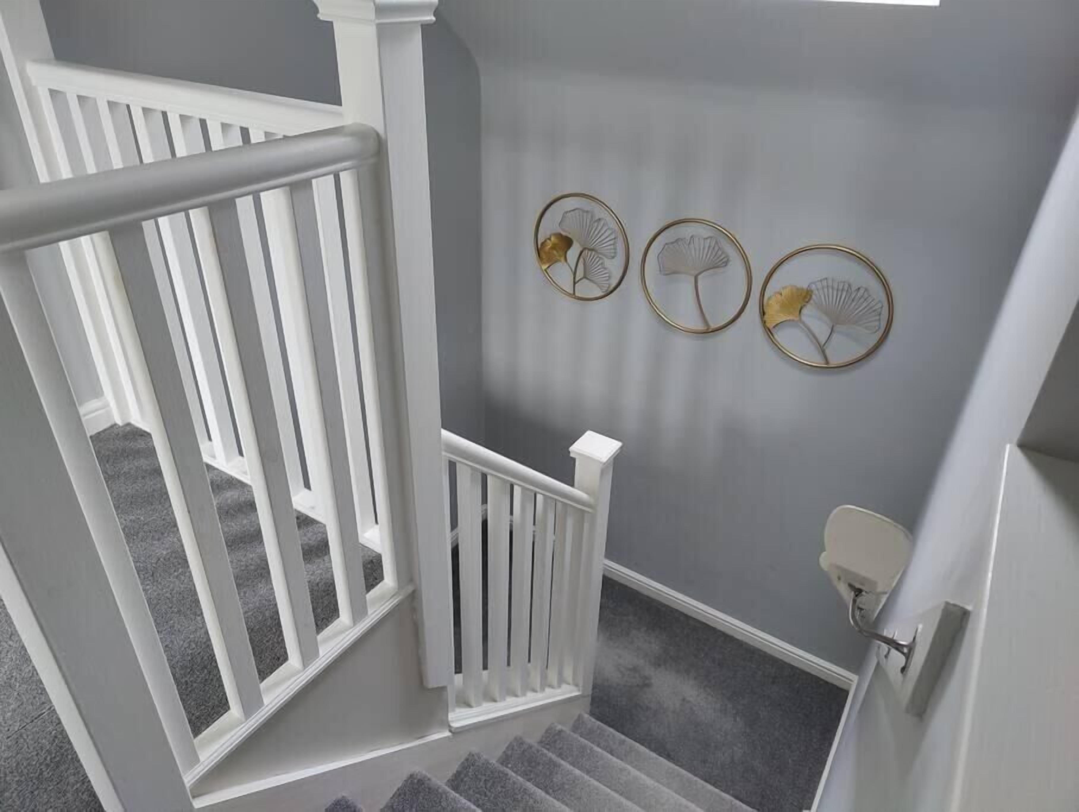A staircase with white railings, grey carpeted steps, and three wall-mounted decorative fans.