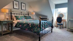 Une chambre à coucher avec un lit, deux tables de chevet, une chaise et une fenêtre.