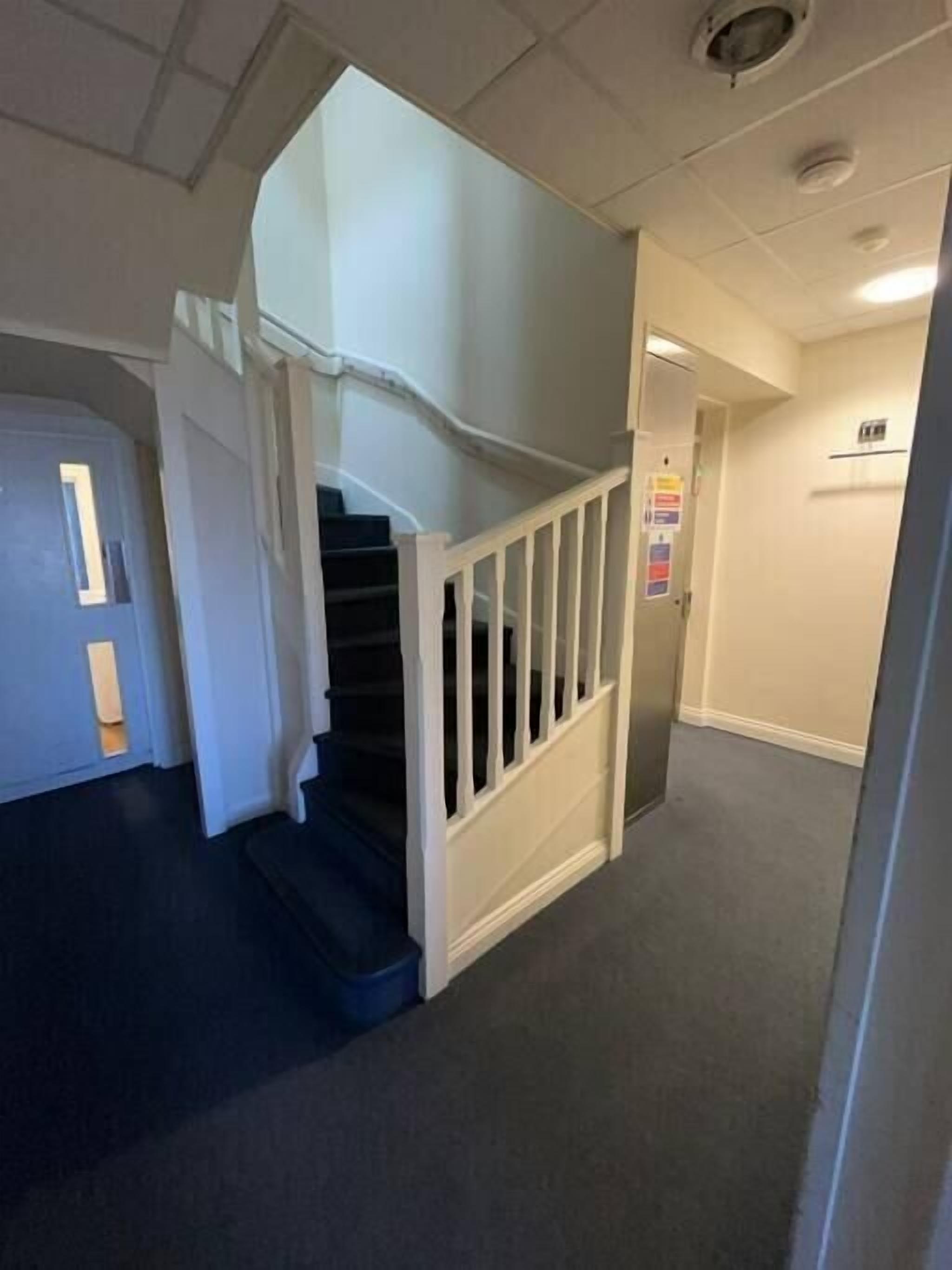 Un escalier avec une rampe blanche et des marches noires menant à l’étage supérieur.