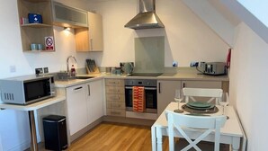 A compact kitchen with a microwave, oven, and sink. There is a small dining table with chairs.