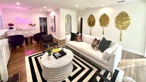 A modern living room with a white sofa, black and white rug, and decorative leaf wall art. - New! Chic Cottage Home W/ Backyard Pool - 12 min to the River Walk! (Alamo Heights)