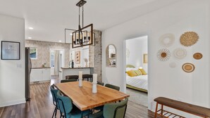A modern kitchen with a wooden table and chairs, a hanging light fixture, and a bench in the corner. - The Suncatcher- Steps to Lake Michigan. Pet Friendly & Fully Fenced (Sheboygan)