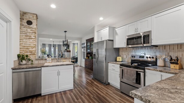 A modern kitchen with white cabinets, stainless steel appliances, and a wooden floor. - The Suncatcher- Steps to Lake Michigan. Pet Friendly & Fully Fenced (Sheboygan)