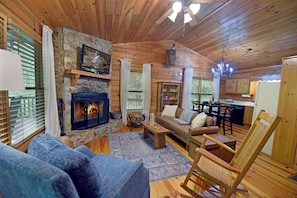 Relax in a warm and inviting space with a stone fireplace, comfortable seating, and a dining area.