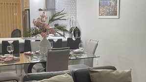 Un salón moderno con una mesa de vidrio, sofá de cuero negro y un jarrón decorativo con flores.
