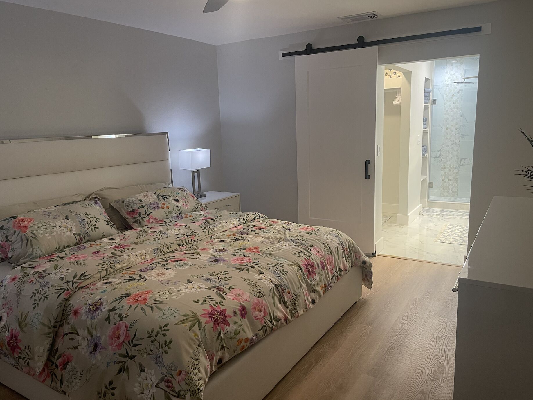 A bedroom with a bed, nightstand, and a sliding door leading to a bathroom.