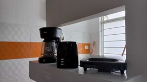 Cuina amb cafetera, torradora i finestra amb persianes.
