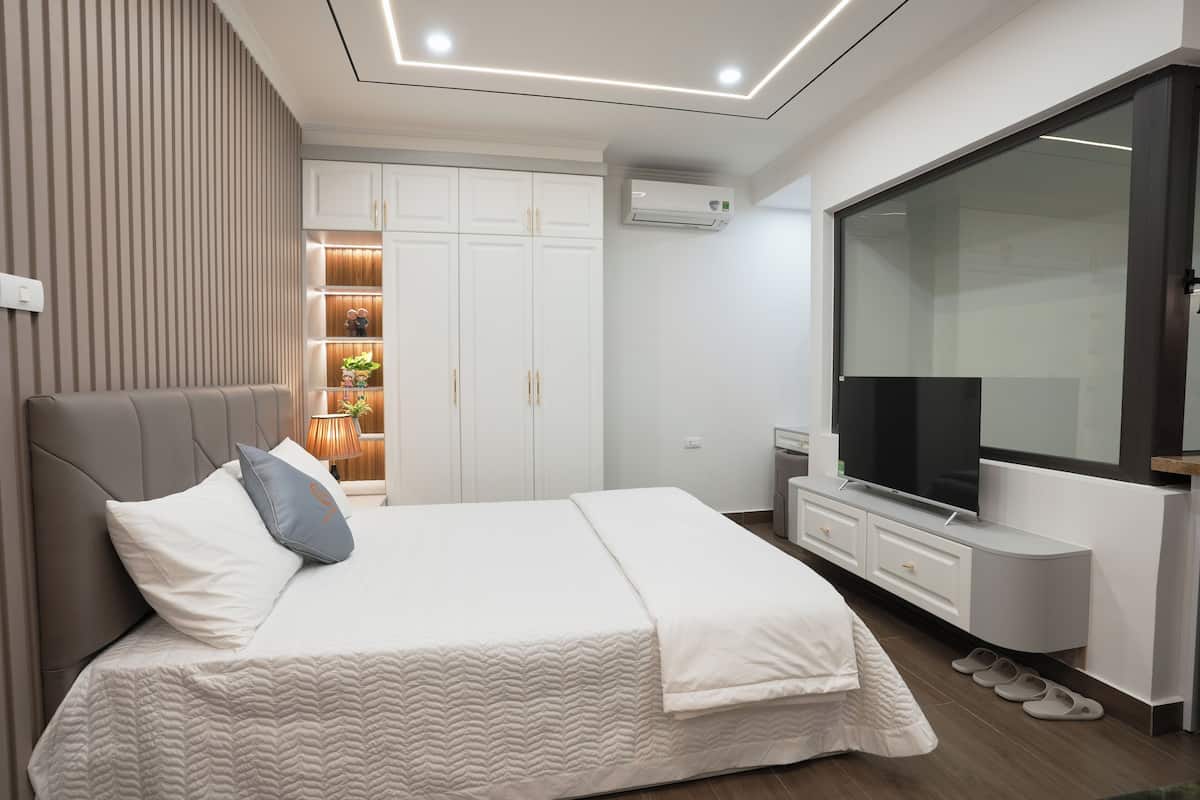 A modern bedroom with a large bed, a TV, and a wardrobe.