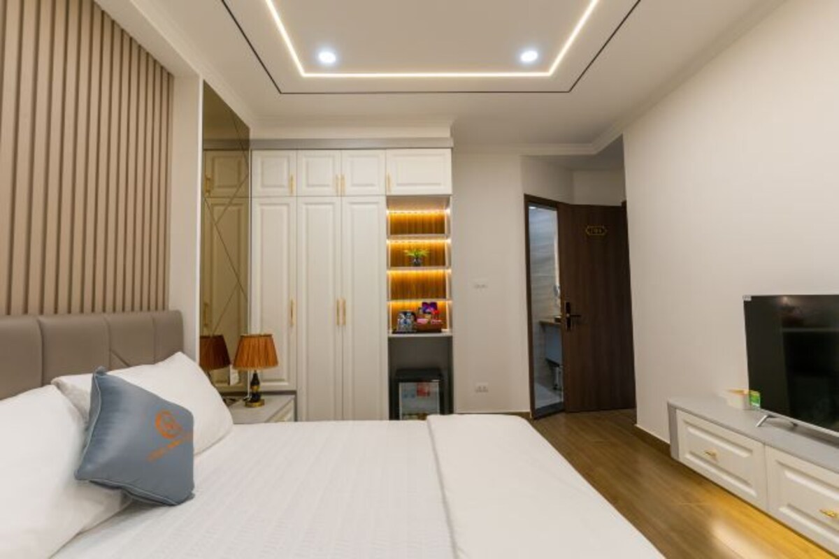 Une chambre d’hôtel moderne équipée d’un grand lit, d’une armoire, d’une télévision et d’un bureau avec une lampe.