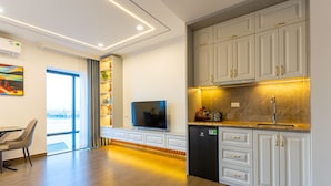 A modern kitchen with white cabinets, a built-in oven, and a black refrigerator. - CM Hotel & Apartment (Hai Phong)