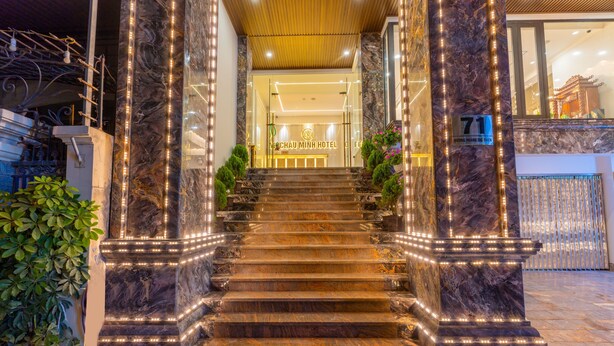 A grand staircase leading to a hotel entrance, flanked by marble columns and illuminated by string lights. - CM Hotel & Apartment (Hai Phong)