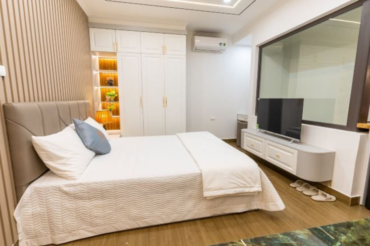 Une chambre à coucher moderne avec un lit, une télévision et une armoire.