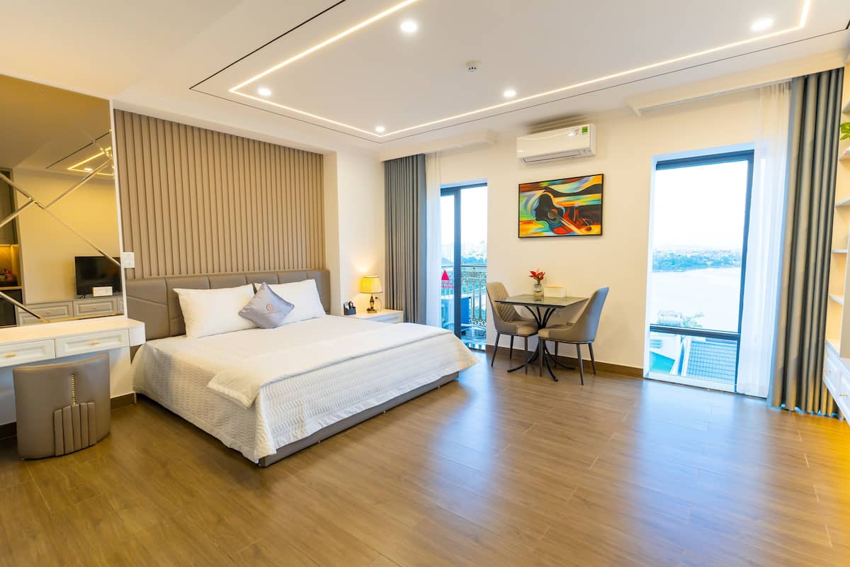 A modern hotel room with a large bed, a desk, and a dining area.