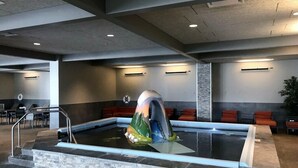 A swimming pool with a colorful sculpture in the center, surrounded by seating areas and a modern ceiling design.