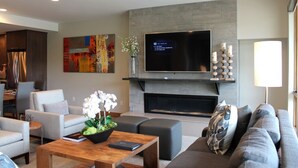 A modern living room with a flat-screen TV, a fireplace, and comfortable seating.