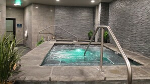 A spa area with a hot tub, metal railings, and stone walls.