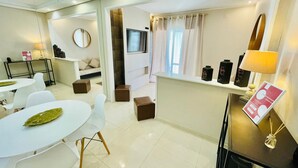 Een moderne hotelkamer met een zithoek, een bank, een televisie en een raam met gordijnen.