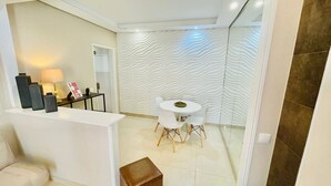 Een moderne woonkamer met een witte bank, een klein bijzettafeltje en een decoratieve wand met een golvend patroon.