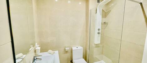 A modern bathroom with a glass-enclosed shower, a white sink, and a toilet.