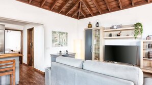 Ein modernes Wohnzimmer mit grauem Sofa, Holzboden und einem Bücherregal sowie einem Fernseher.