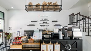 A coffee shop counter with a menu board, coffee machines, and a variety of coffee products displayed. - Le Palmier Phu Quoc Hotel (Phu Quoc)