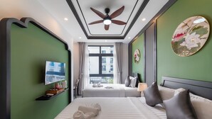 A hotel room with two beds, a ceiling fan, a TV, and a window with a view of buildings. - Le Palmier Phu Quoc Hotel (Phu Quoc)