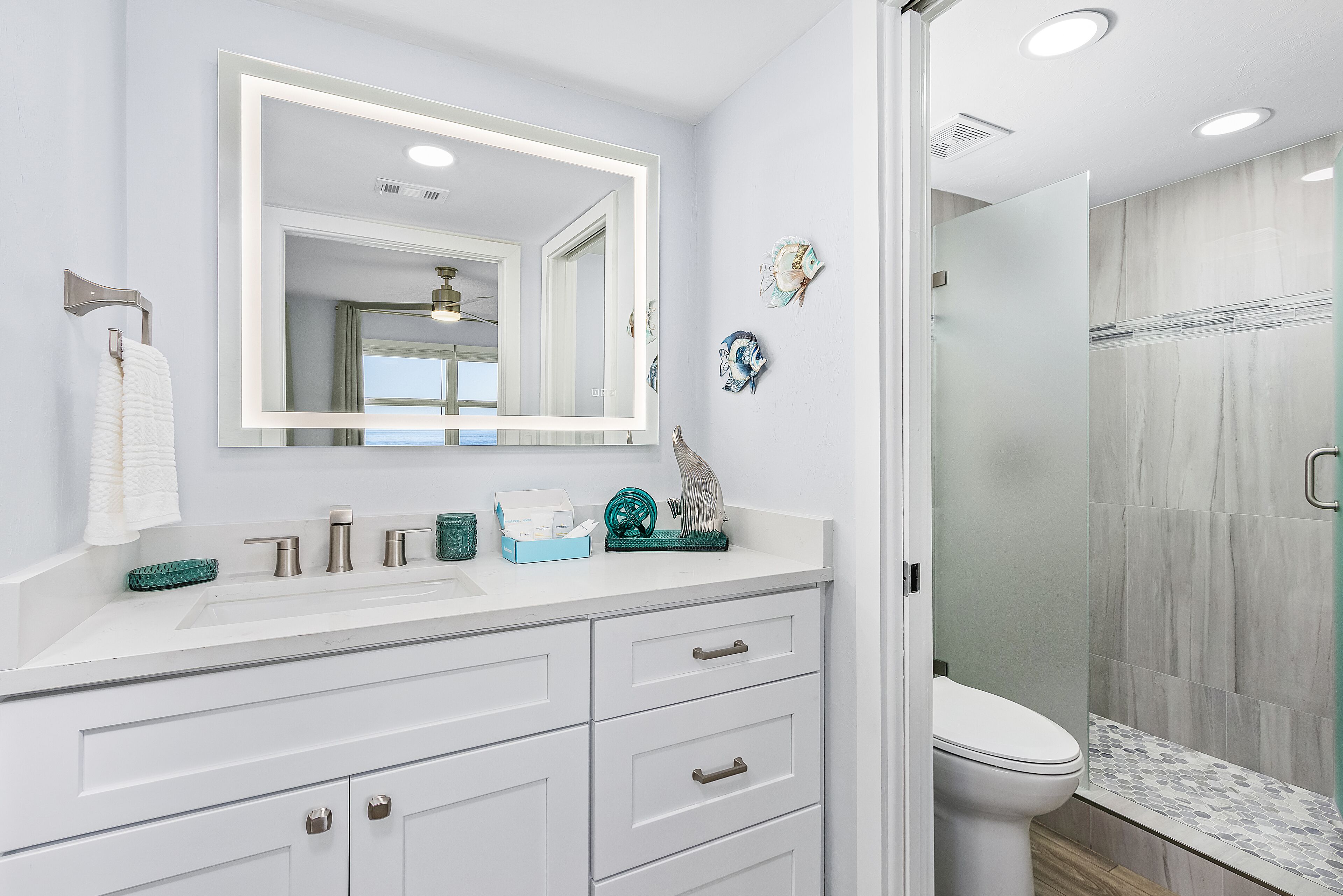 Un bagno con un mobile lavabo bianco, uno specchio grande, un water e uno spazio doccia.