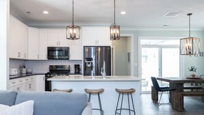 Una cocina moderna con armarios blancos, electrodomésticos de acero inoxidable y una isla central con taburetes.