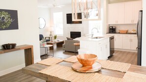 Una cocina moderna con una isla central, muebles blancos y un refrigerador negro.