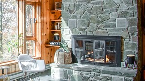 A cozy room with a stone fireplace, wooden shelves, and a large window. - 3 Br: N Westridge 222-7 Alpenglow: 3BR,2 Bath (Snowshoe)