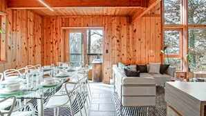 A wooden cabin interior with a dining area, a sofa, and large windows. - 3 Br: N Westridge 222-7 Alpenglow: 3BR,2 Bath (Snowshoe)